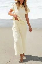 Model walking on beach in Apricot Lattice Two Piece Set, featuring soft flared pants and casual top.