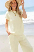 Model smiling in Apricot Lattice Set - Two Piece with batwing top and flared pants, styled for beachwear.