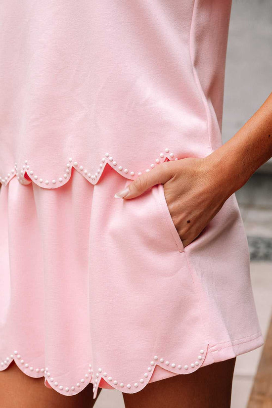 Close-up of a pink skort set  with scalloped hem and pearl details.