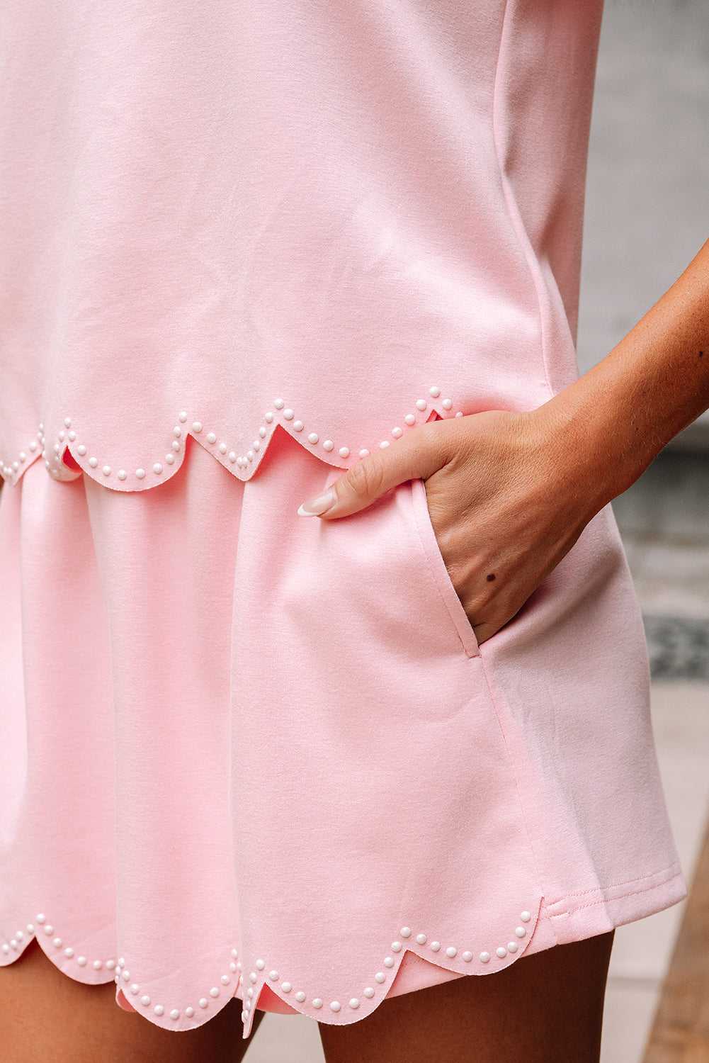 Close-up of a pink skort set  with scalloped hem and pearl details.