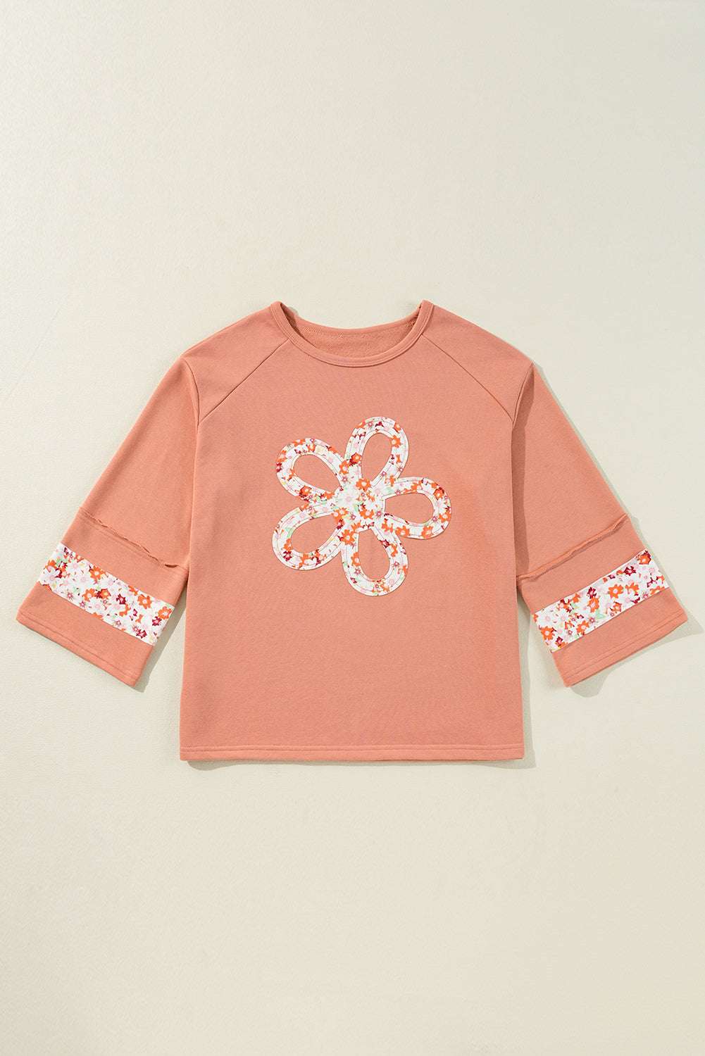 Flat lay of Flower Patch Graphic Top featuring floral patchwork on front and sleeves, showcasing its versatile fit and spring-ready design.
