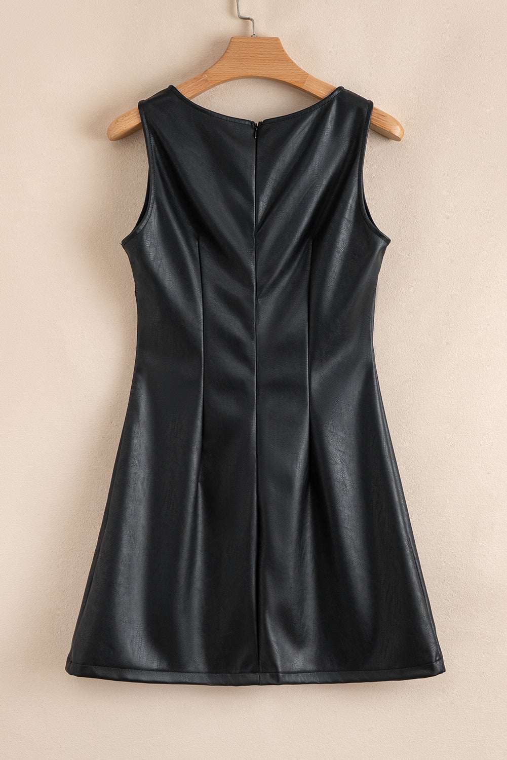 Back of Black Vegan Leather Sleeveless Mini Dress on hanger, emphasizing the structured seams and hidden zipper for a clean finish.