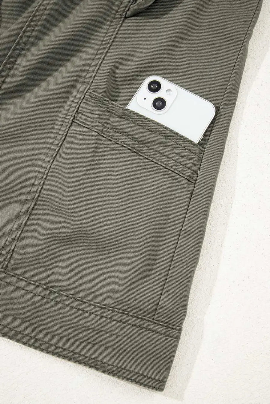 Side pocket of Green Bay Ruffled Denim Vest - Women's Fashion Trends shown holding a smartphone, emphasizing functionality and style.