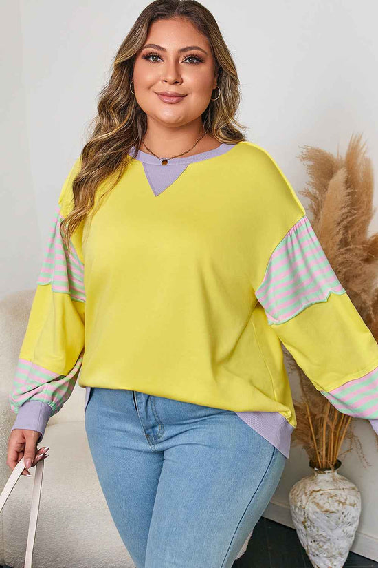 Trendy plus size yellow sweatshirt with lilac accents and striped sleeves, styled for a relaxed autumn outfit.