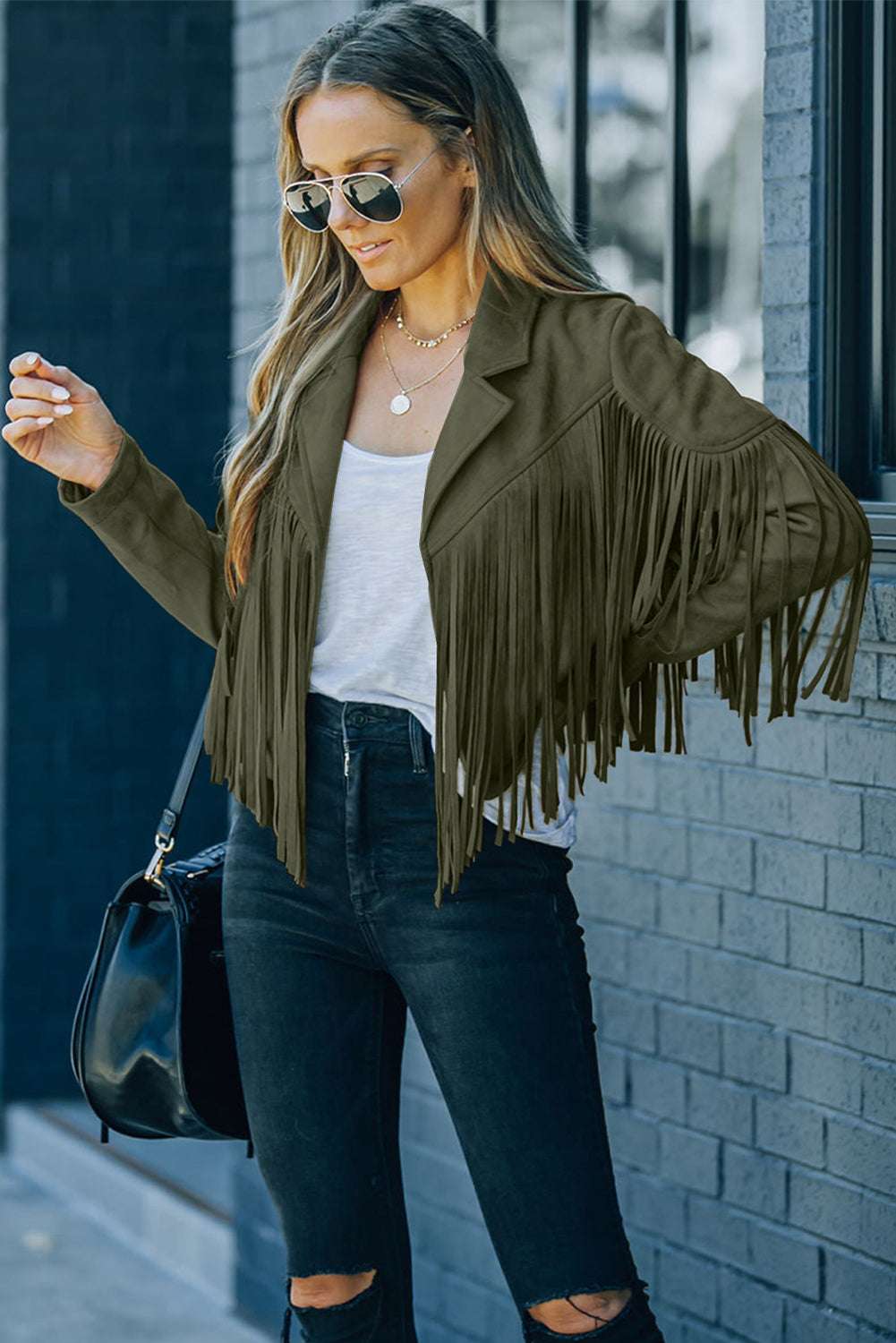 Green cropped fringe faux suede jacket styled with black skinny jeans and sunglasses, perfect for casual fall western-inspired outfits.