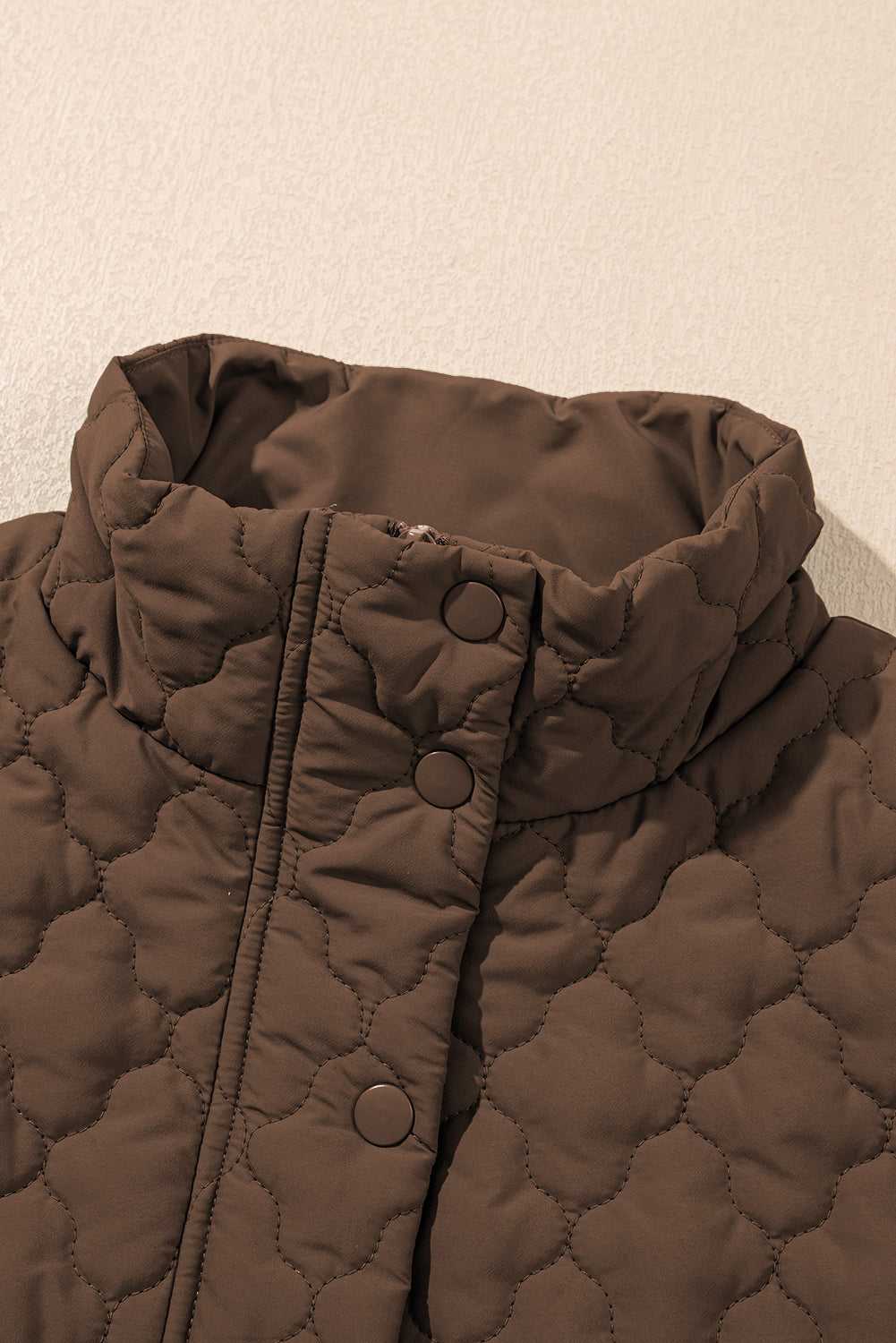 Close-up of high collar and snap buttons on brown Flower‑Quilted Winter Gilet, highlighting padded warmth and floral quilted texture.