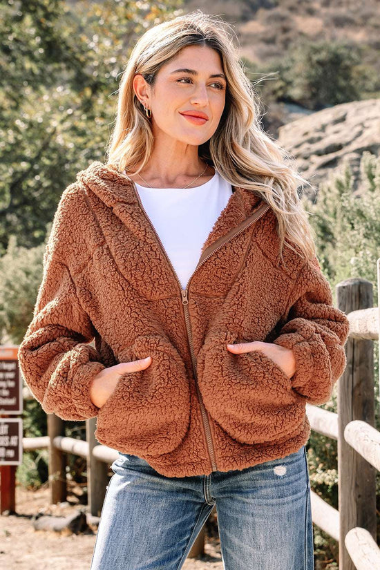 Women's Zip‑Up Sherpa Hoodie Jacket in brown with plush fleece texture, styled casually with jeans for winter comfort outdoors.