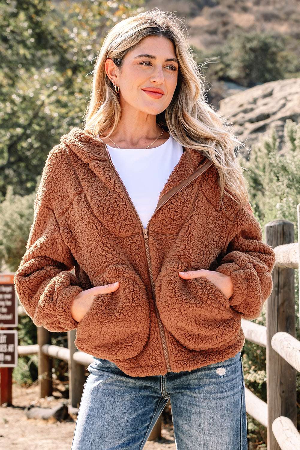 Women's Zip‑Up Sherpa Hoodie Jacket in brown with plush fleece texture, styled casually with jeans for winter comfort outdoors.