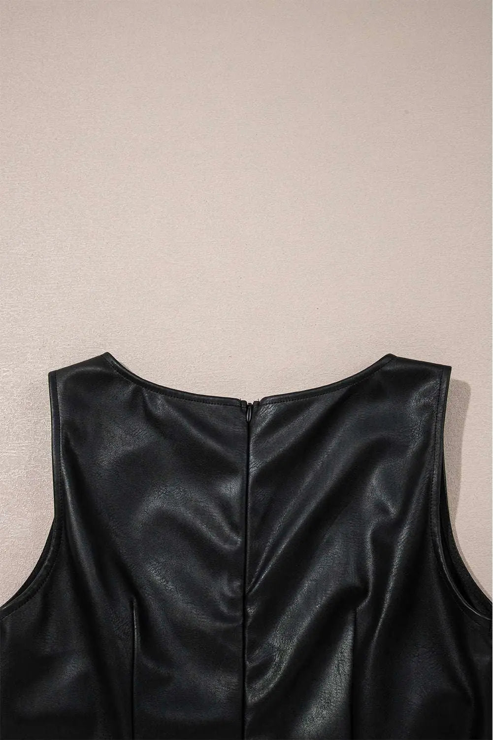 Detailed view of back zipper on Black Vegan Leather Sleeveless Mini Dress, designed for easy wear and seamless style by FashionFitz.