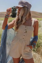 Beige Shirred Playsuit with front buttons styled for a casual summer look, featuring a fitted bodice and flowy shorts in a sunny outdoor setting.