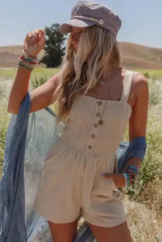 Beige Shirred Playsuit with front buttons styled for a casual summer look, featuring a fitted bodice and flowy shorts in a sunny outdoor setting.