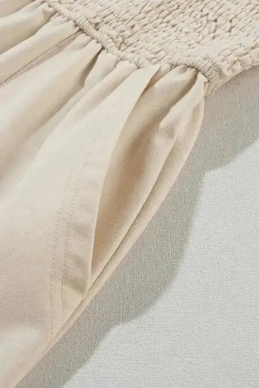 Close-up of Beige Shirred Playsuit fabric showing ruched bodice and soft pleated bottom. Lightweight material ideal for casual summer wear.