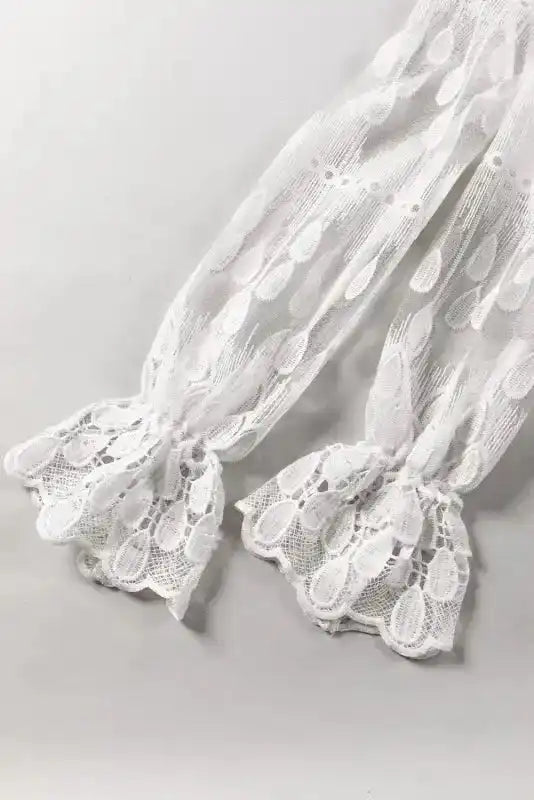 Flounce sleeve detail of beige embroidered mesh blouse. Features scalloped lace cuffs and sheer embroidered fabric.