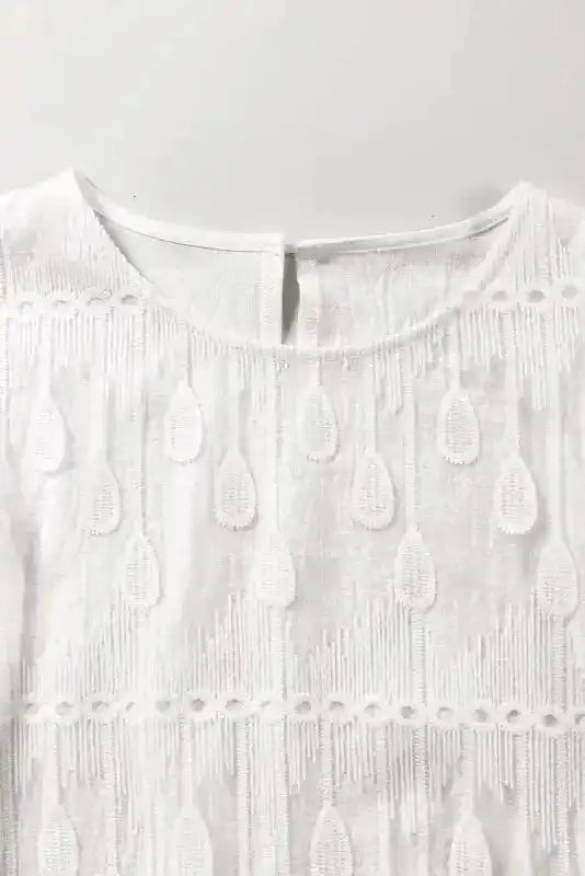 Close-up of neckline and back button detail on beige embroidered mesh blouse. Features teardrop embroidery and soft mesh fabric.