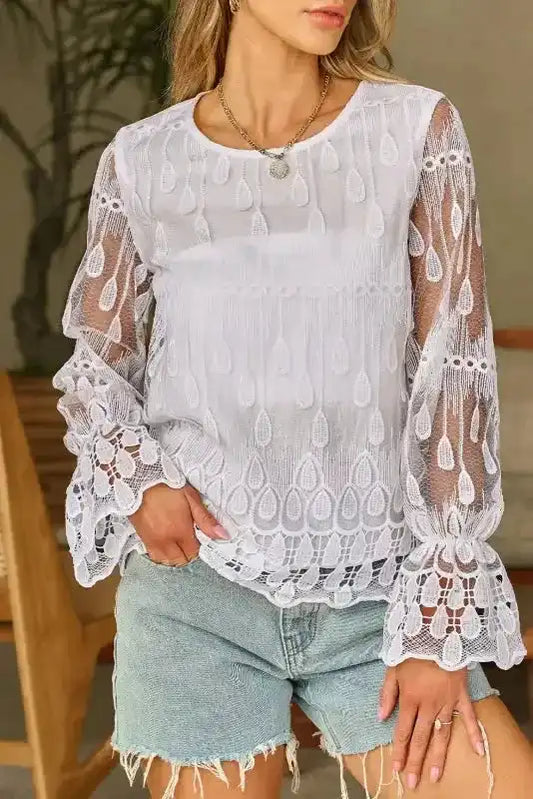 Beige embroidered mesh blouse with flounce sleeves styled with denim shorts. Lightweight sheer fabric ideal for casual chic looks.