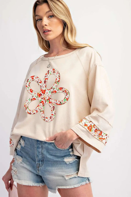 Beige Flower Graphic Top featuring bold floral patchwork design and exposed seams, paired with ripped shorts for a trendy casual look.