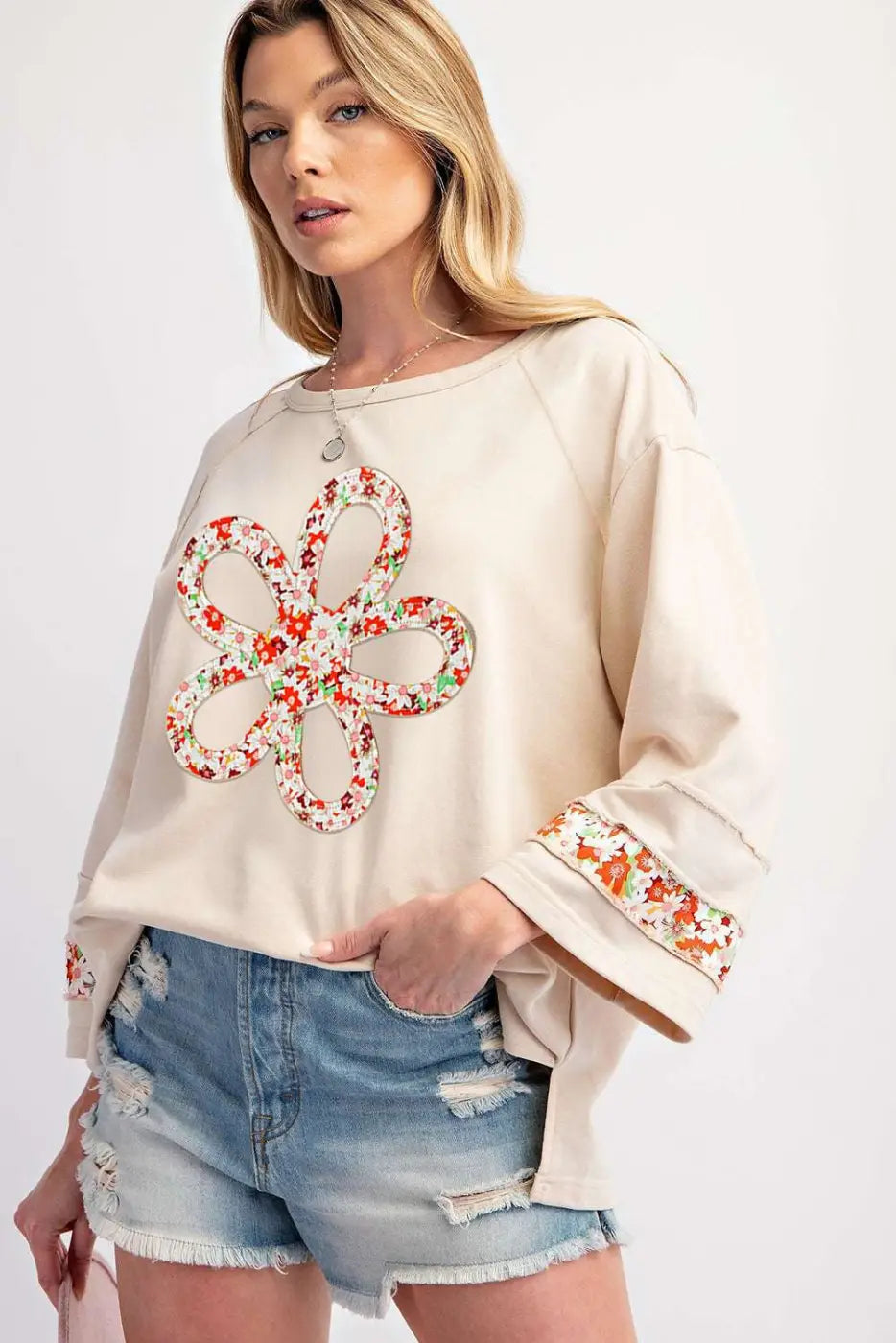 Beige Flower Graphic Top featuring bold floral patchwork design and exposed seams, paired with ripped shorts for a trendy casual look.