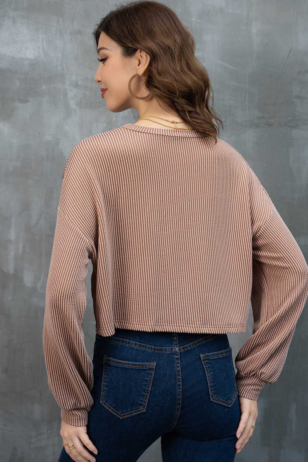 Woman wearing a Game Day Graphic Crop Top and blue jeans against a gray background