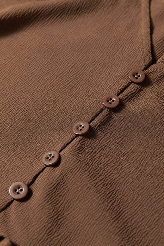 Detail shot of button front on Brown Long Sleeve Tiered Maxi Dress, highlighting fine stitching and textured fabric.