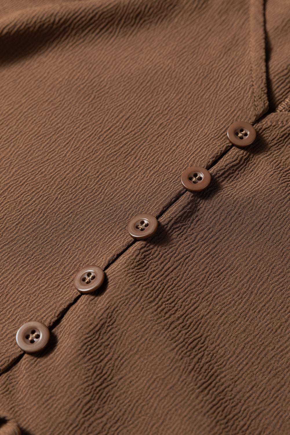 Detail shot of button front on Brown Long Sleeve Tiered Maxi Dress, highlighting fine stitching and textured fabric.