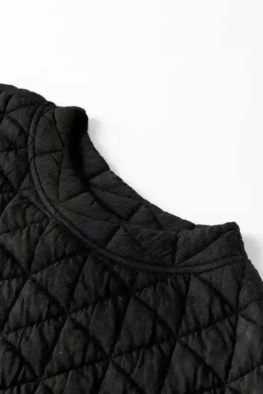 Close-up of black quilted neckline from cozy loungewear top, featuring soft fabric and modern stitching.