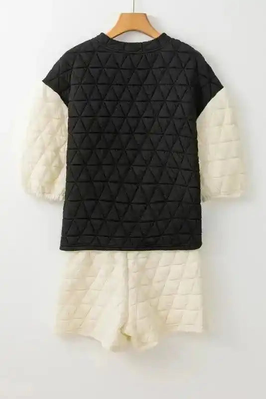 Rear view of black and cream quilted loungewear set on hanger showing soft, textured design for modern style.