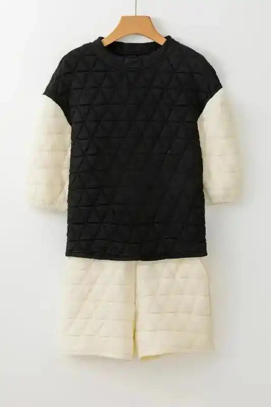 Black quilted top with cream sleeves and matching cream shorts set displayed on hanger for cozy fashion appeal.