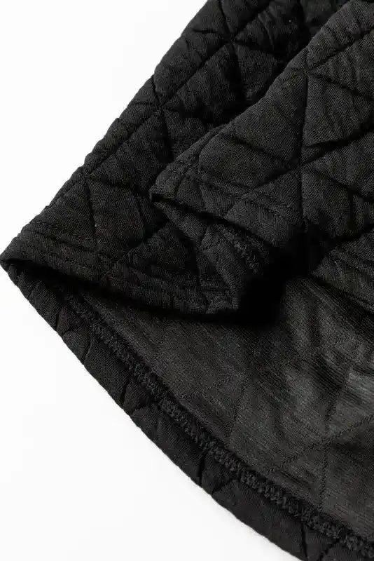 Detail of black quilted top hem from modern style loungewear set, showing soft inner lining and stitching.