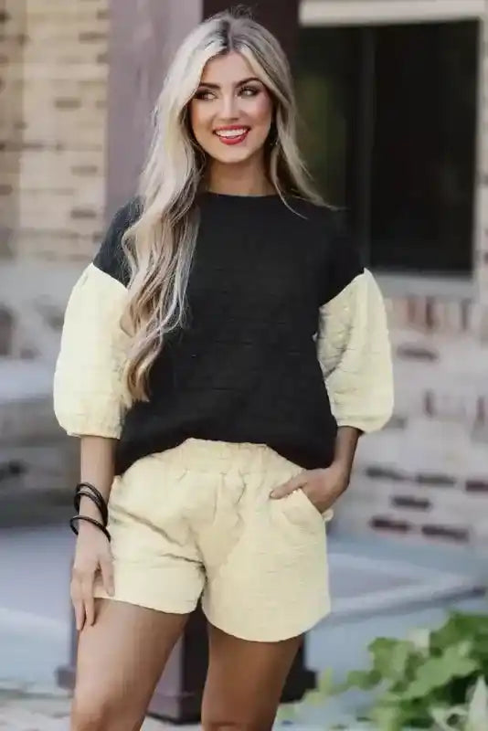 Model wearing modern black and cream quilted loungewear set with high waist shorts and puff sleeves.