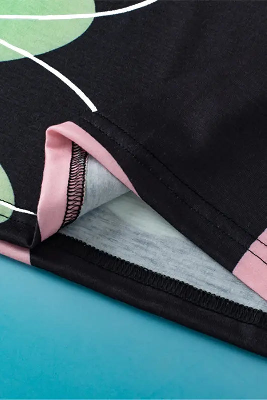 Close-up of a black sports bra with pink trim and green floral pattern from black floral t shirt