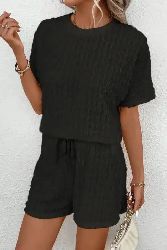 Casual black co-ord set for women with textured fabric, short sleeves, and drawstring shorts. Perfect for home or vacation wear.