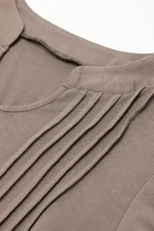 Close-up of pleated detailing on taupe Notched Pleat Puff Sleeve Shift T-Shirt Dress, showcasing soft fabric texture.