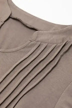 Close-up of pleated detailing on taupe Notched Pleat Puff Sleeve Shift T-Shirt Dress, showcasing soft fabric texture.