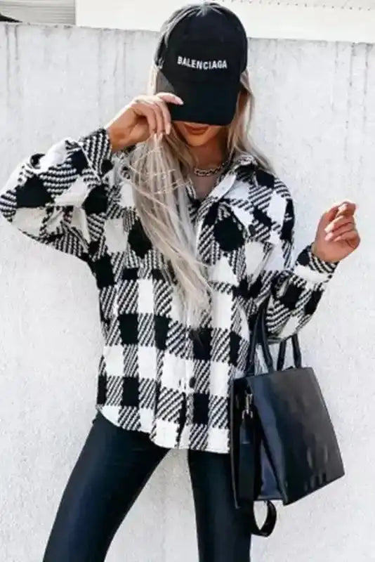 Modern black plaid shacket for winter outfits styled with a black cap and handbag, great for casual winter fashion.