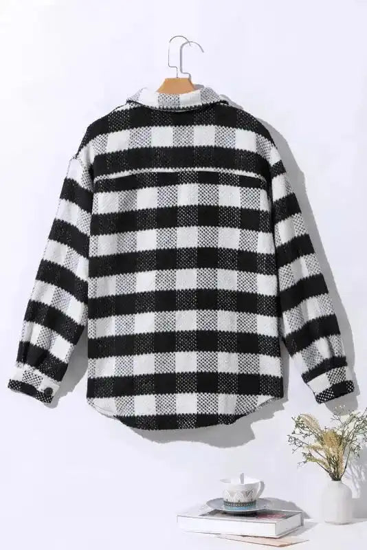 Back view of black plaid shacket for winter outfits on hanger, showing classic check pattern and curved hem design.