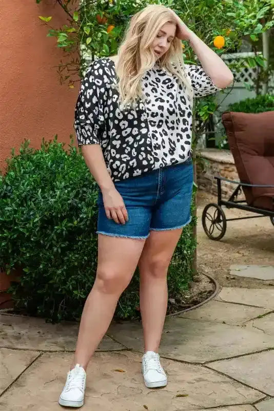 Black & white leopard print plus size blouse with smocked half sleeves, paired with denim shorts and white sneakers.