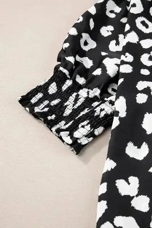Detail of smocked cuff on black and white leopard print plus size blouse, highlighting comfortable and stylish sleeve design.