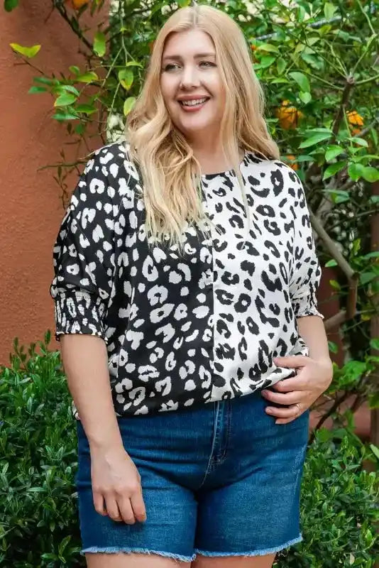 Plus size black and white leopard print blouse with half sleeves, styled casually with denim shorts for summer wear.