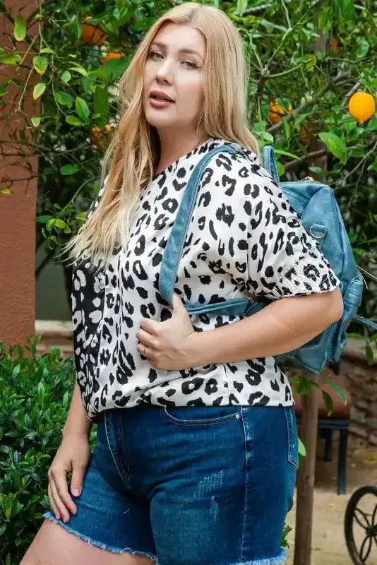 Plus size leopard print blouse in black and white, styled with denim shorts and a backpack for a casual western vibe.