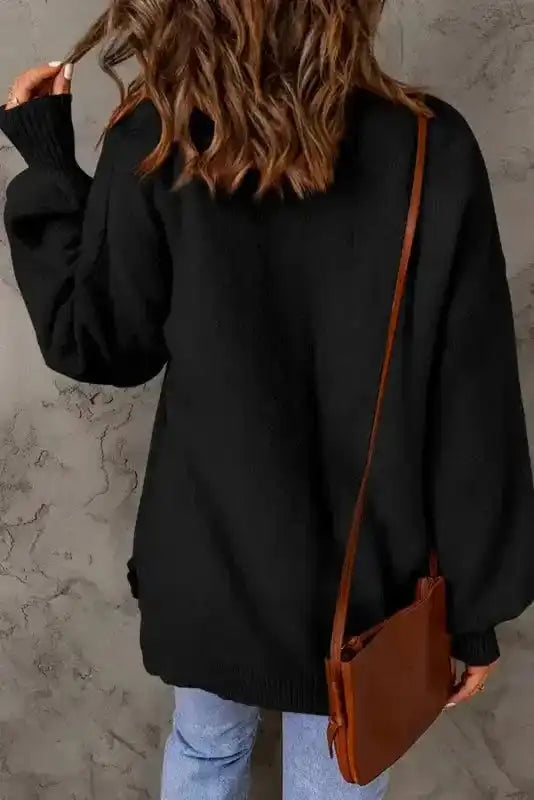 Back view of black pocketed sweater with puffy sleeves, showcasing relaxed fit and ribbed cuffs, ideal for autumn and winter outfits.