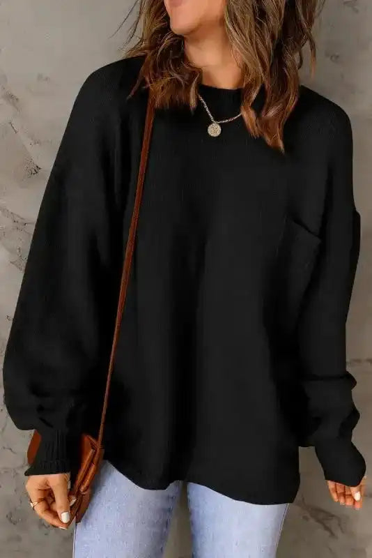 Front view of black puffy sleeve sweater featuring a chest pocket and crew neckline, paired with denim jeans for a cozy casual look.