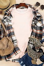 Flat lay of light pink plus size T-shirt styled with plaid shirt, leopard boots, and tan accessories for a cozy fall look.