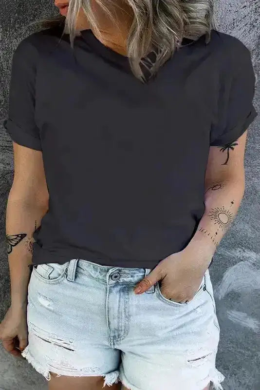 Ladies black plus size T-shirt with round neck and rolled sleeves, styled casually with ripped denim shorts for a summer look.