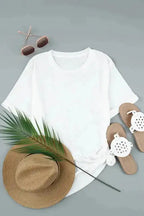 Flat lay of white plus size T-shirt with rolled sleeves, paired with summer accessories like sandals, hat, and sunglasses.