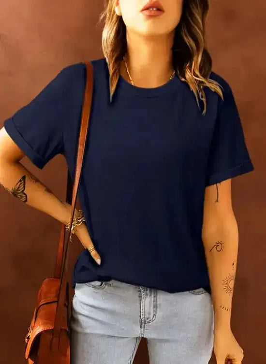 Navy blue plus size T-shirt with round neck and rolled sleeves, styled with jeans and a brown crossbody bag for a casual look.