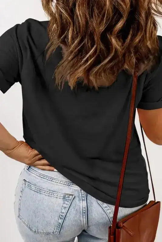 Back view of black plus size T-shirt featuring rolled sleeves and relaxed fit, paired with light-wash jeans for a casual outfit.