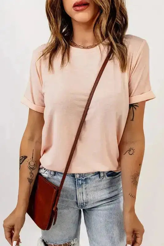 Light pink plus size T-shirt with round neck and rolled sleeves, styled with ripped jeans and a brown crossbody bag.