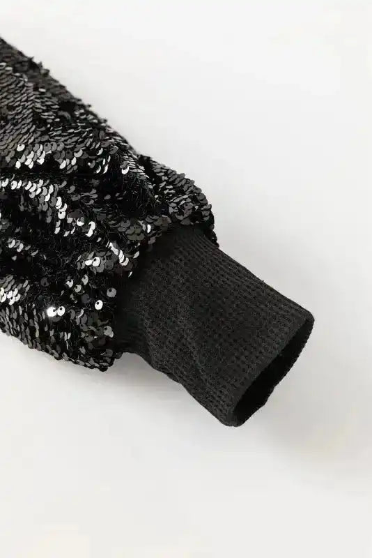 Close-up of the sequin lantern sleeve cuff on the Black Sequin Blouse, emphasizing the textured knit and shimmering embellishments.