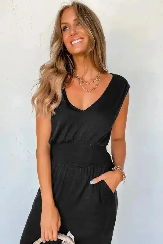 Close-up of Black Shirred Jumpsuit V-Neck highlighting the shirred waist and soft linen fabric, styled with layered gold jewelry.