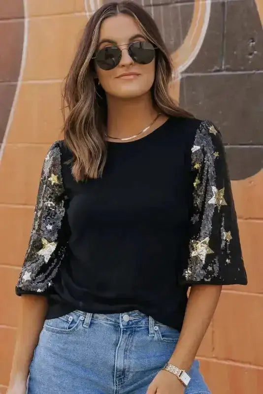 Shine in Style: Black Star Sequin Top with half sleeves and gold star embellishments, paired with denim jeans for a chic casual look.